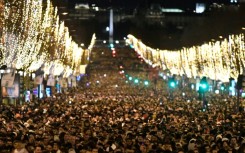 People gather on the Champs-Elysees as they wait for the New Year's Eve fireworks in Paris on December 31, 2022