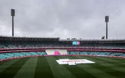 Ground staff stand near covers placed over the pitch during a rain delay on day three of the third cricket Test match between Australia and South Africa at the Sydney Cricket Ground