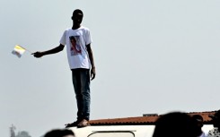 Greeting: A young man waves a flag to welcome the pope