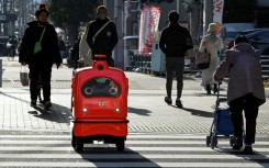 A four-wheeled robot dodges pedestrians on a street outside Tokyo, part of an experiment businesses hope will tackle labour shortages and rural isolation