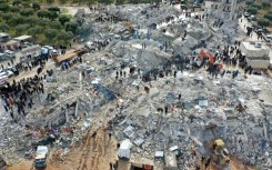 An aerial view of residents searching for survivors in the Syrian village of Besnia in rebel-held Idlib province