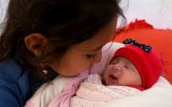 Khalil al-Suwadi's daughters gathered around the baby, embracing and kissing her