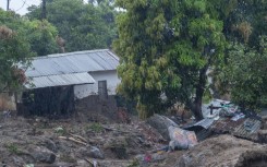 People walk across a makeshift bridge over flood water in Blantyre on Tuesday