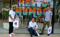 Apple fans pose outside the company's new Mumbai store during a media preview