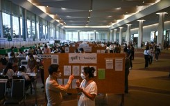 A voter (R) asks for directions to cast her ballot at a polling station inside a shopping mall in Bangkok