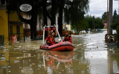 Volunteer firefighters ride their dinghy across a street flooded by the river Savio in the Ponte Vecchio district of Cesena, central eastern Italy, on May 17, 2023