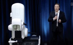 Elon Musk standing next to a surgical robot during a Neuralink presentation in 2020