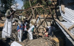 Local Red Cross volunteers attempt to extract a corpse from the rubble of a house destroyed by a landslide