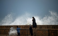 People take photos by a waterfront in Karachi as Cyclone Biparjoy approaches on Wednesday