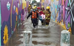 A handout picture released by the Rio Grande do Sul State Government shows firemen carrying a person in a flooded street in Porto Alegre, Rio Grande do Sul State, Brazil