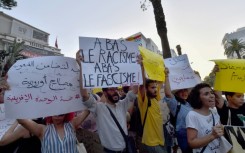 Demonstrators lift placards and chant anti-racism slogans during a protest in Tunis in support of migrants