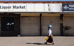 A woman walks past a closed liquor shop in Soweto after President Cyril Ramaphosa suspended alcohol sales.