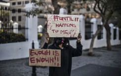 A woman holds placards as she demonstrates against gender-based violence outside Parliament.