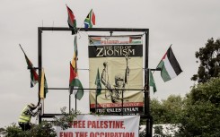 File: A volunteer is seen climbing a ladder next to a billboard structure during a pro-Palestinian demonstration. AFP/Luca Sola