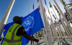 A worker prepares to hoist a United Nations flag with other national flags of participating countries at the venue of the COP28 UN climate summit in Dubai on November 30, 2023. The UN climate conference opens in Dubai on November 30 with nations under pressure to increase the urgency of action on global warming and wean off fossil fuels, amid intense scrutiny of oil-rich hosts UAE.