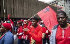 File: A man (C) holding a flag of the South African Communist Party (SACP) in Johannesburg, South Africa. 