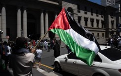 A man holds a Palestinian flag as they take part in a pro-Palestinian demonstration outside the High Court in Cape Town. AFP/Rodger Bosch