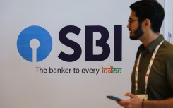 A man walks past a State Bank of India (SBI) logo. NurPhoto via AFP/Niharika Kulkarni