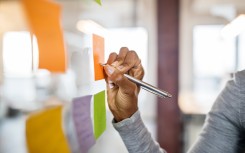 File: A woman/student writing on a sticky note. Getty Images/Luis Alvarez