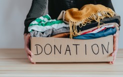 File: A woman holding a donation box filled with clothes. GettyImages/Damian Lugowski