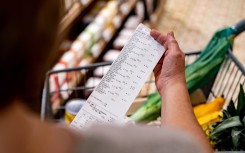 File: A shopper looking at a receipt in a supermarket. GettyImages/andresr