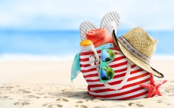 File: Beach bag, straw hat, flip flops, sunglasses and starfish on sandy beach. Getty Images/igoriss