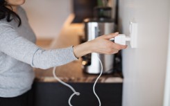 File: A woman plugging in a mobile phone charger on wall. GettyImages/Maskot