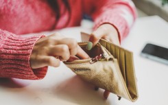 File: A woman looking for money in a wallet. GettyImages/Carol Yepes