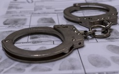 File: Handcuffs and a fingerprint card. GettyImages/Daniel Tamas Mehes