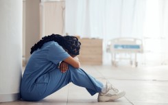 File: A nurse suffering from depression and burnout sitting on the floor. GettyImages/Jacob Wackerhausen