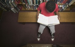 File: A young boy reading a book in a library. GettyImages/Andersen Ross Photography Inc