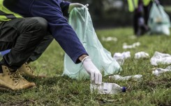 File: A volunteer picking up a plastic bottle during a park clean-up action. GettyImages/vm