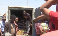 Police keeping an eye on people as they remove food from a spaza shop. 