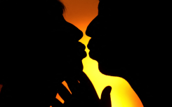 File: An illustrated picture shows a man and a woman kissing in front of the sunset.