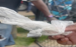 A resident holds a packet of food sold at a spaza shop.