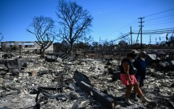 Residents look for belongings through the ashes of their family’s home