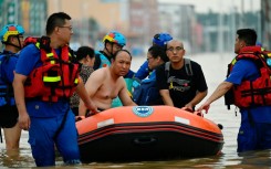 Rescuers wade in a flooded road as they evacuate residents following heavy rains in Zhuozhou, in northern China's Hebei province on August 2, 2023