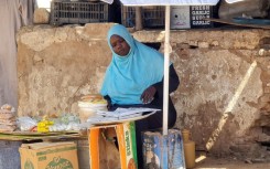 A woman sells foodstuffs at a stall in a Khartoum street as she tries to make a living amid the near-daily air strikes and artillery bombardments