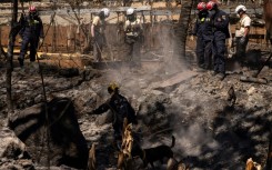 Search and recovery team members check charred buildings and cars in the aftermath of the Maui wildfires in Lahaina