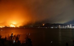 The McDougall Creek wildfire burns in the hills outside West Kelowna, British Columbia, on August 17, 2023, as seen from the nearby city of Kelowna