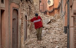 A Marrakesh resident clambers over the rubble of a home blocking one of the city's historic alleyways