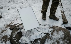 A Ukrainian serviceman stands next to the antenna of a Starlink satellite-based broadband system in Bakhmut in February 2023