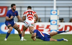 France's Maxime Lucu (R) and Charles Ollivon (L) tackle Japan's Siosaia Fifita (C)