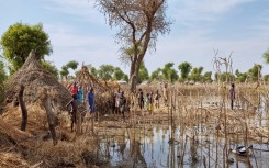 Children stand among the rooftops of homes destroyed by floodwaters in Yusuf Batir refugee camp in Maban, South Sudan, on November 25, 2019 -- UNICEF says tens of millions of children were displaced by climate disasters from 2016 to 2021