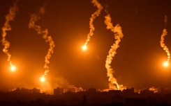 Flares dropped by Israeli forces illuminate the night sky above the Gaza Strip