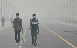 Smog-choked: People wearing face masks walk along the Kartavya Path in New Delhi on Sunday