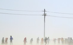 People walk through a dust storm on a hot summer day in India in April 2023.