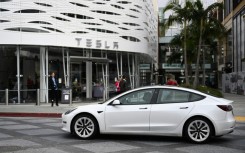 A Tesla electric vehicle drives past the Tesla Inc Santa Monica Place store, in Santa Monica, California