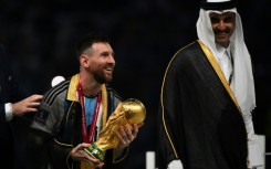 Lionel Messi holds the World Cup trophy next to Qatar's Emir Sheikh Tamim bin Hamad al-Thani after Argentina's victory in 2022