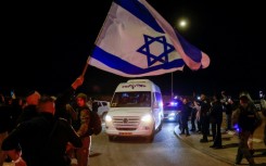 A man waves an Israeli flag as a vehicle carrying two newly freed women hostages with Russian citizenship passes in southern Israel on November 29, 2023